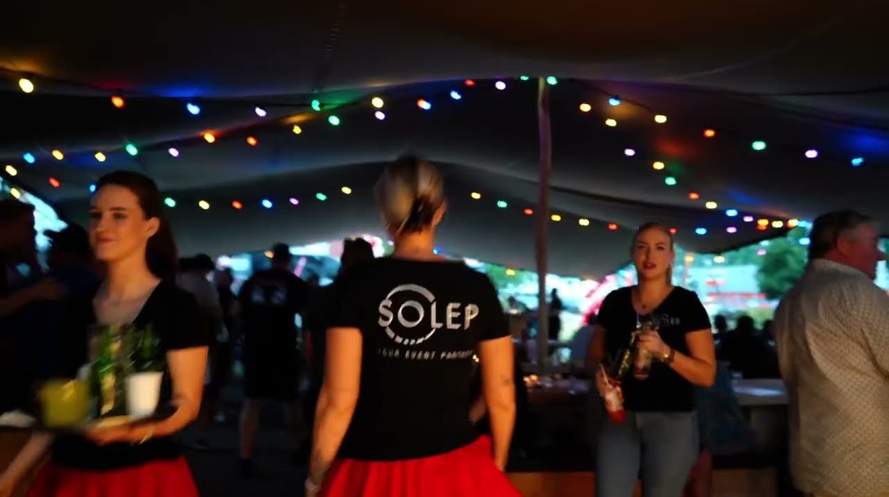 Gasten in een tent met lichtslingers tijdens de zomer-BBQ