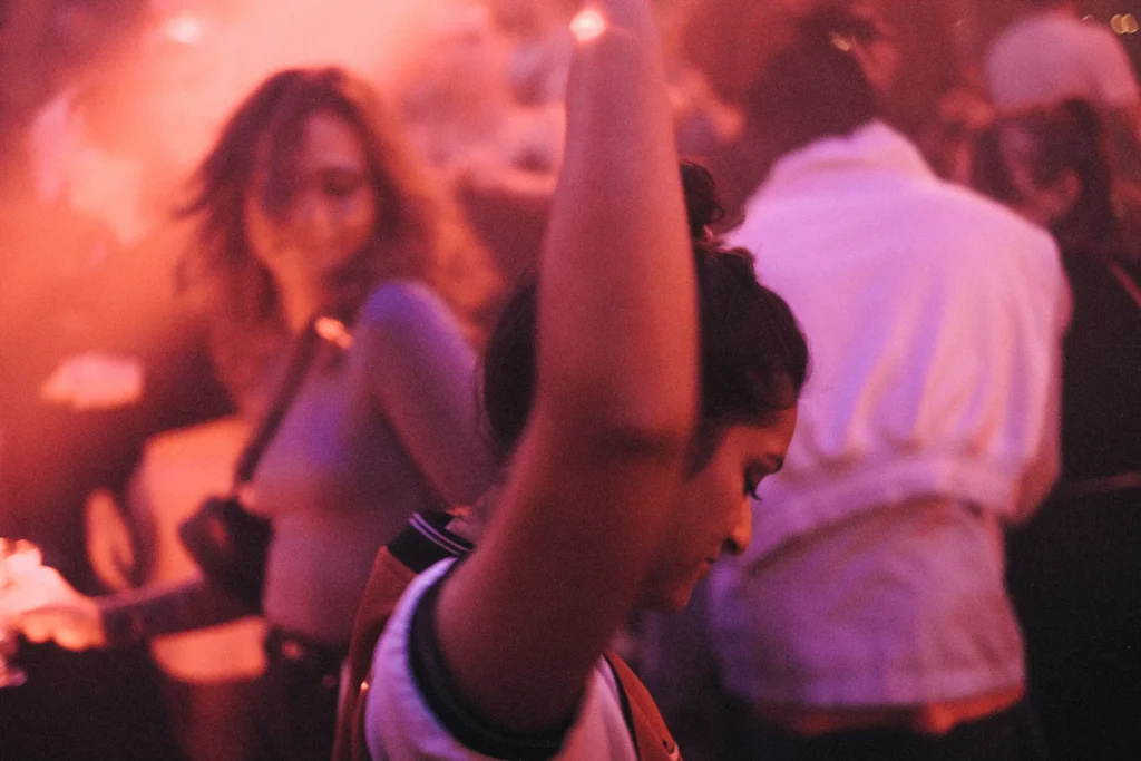 Feestgangers met de handen in de lucht in roze licht