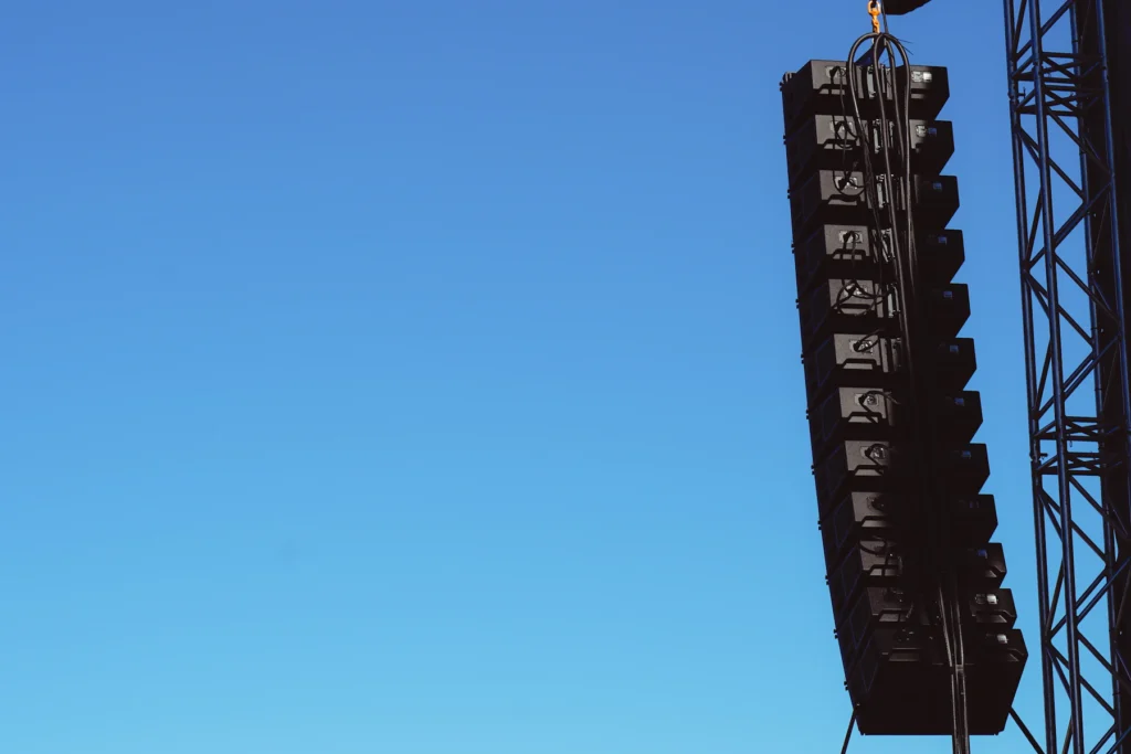 Line-array speakers aan een truss tegen een blauwe lucht